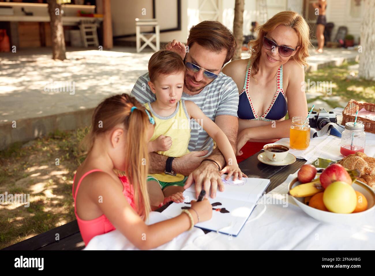Tochter, die einem kleinen Bruder zeigt, wie man zeichnet Außentisch Stockfoto