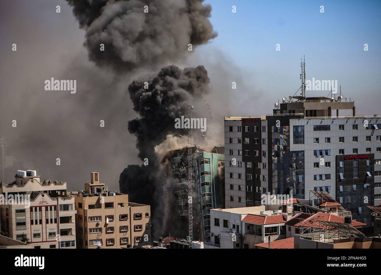 Gazastreifen, Palästina. 15 2021. Mai: Der Rauch steigt, wenn das Gebäude einstürzt, nachdem ein israelischer Luftangriff den Al-Jalaa-Turm getroffen hat, der Wohnungen und mehrere Medien beherbergt, darunter die Associated Press und Al Jazeera, in Gaza-Stadt, 15. Mai 2021. Als Reaktion auf die Tage der gewalttätigen Auseinandersetzungen zwischen israelischen Sicherheitskräften und Palästinensern in Jerusalem starteten verschiedene palästinensische Gruppen von Aktivisten in Gaza seit dem 10. Mai Raketenangriffe, bei denen bis heute mindestens neun Israelis getötet wurden. Nach Angaben des palästinensischen Gesundheitsministeriums, mindestens 139 Palästinenser, darunter 39 Kinder, w Stockfoto