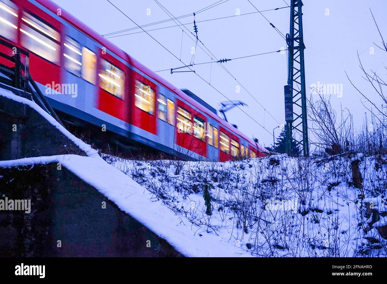 Eine schnell fahrende S-Bahn über eine Brücke in einer winterlichen Landschaft. Stockfoto