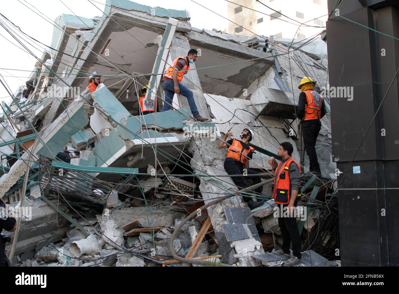 Gaza-Stadt, israelischer Luftangriff in Gaza-Stadt. Mai 2021. Retter überprüfen die Trümmer des Jala-Turms, der Büros von Al-Jazeera TV und Associated Press sowie Wohnwohnungen beherbergte, nachdem er am 15. Mai 2021 von einem israelischen Luftangriff in Gaza-Stadt getroffen wurde. Israel sagte am Samstag, dass es das Hochhaus in Gaza-Stadt, in dem internationale Medien untergebracht sind, getroffen habe, weil es Vermögenswerte des Hamas-Geheimdienstes enthielt. Kredit: Rizek Abdeljawad/Xinhua/Alamy Live Nachrichten Stockfoto