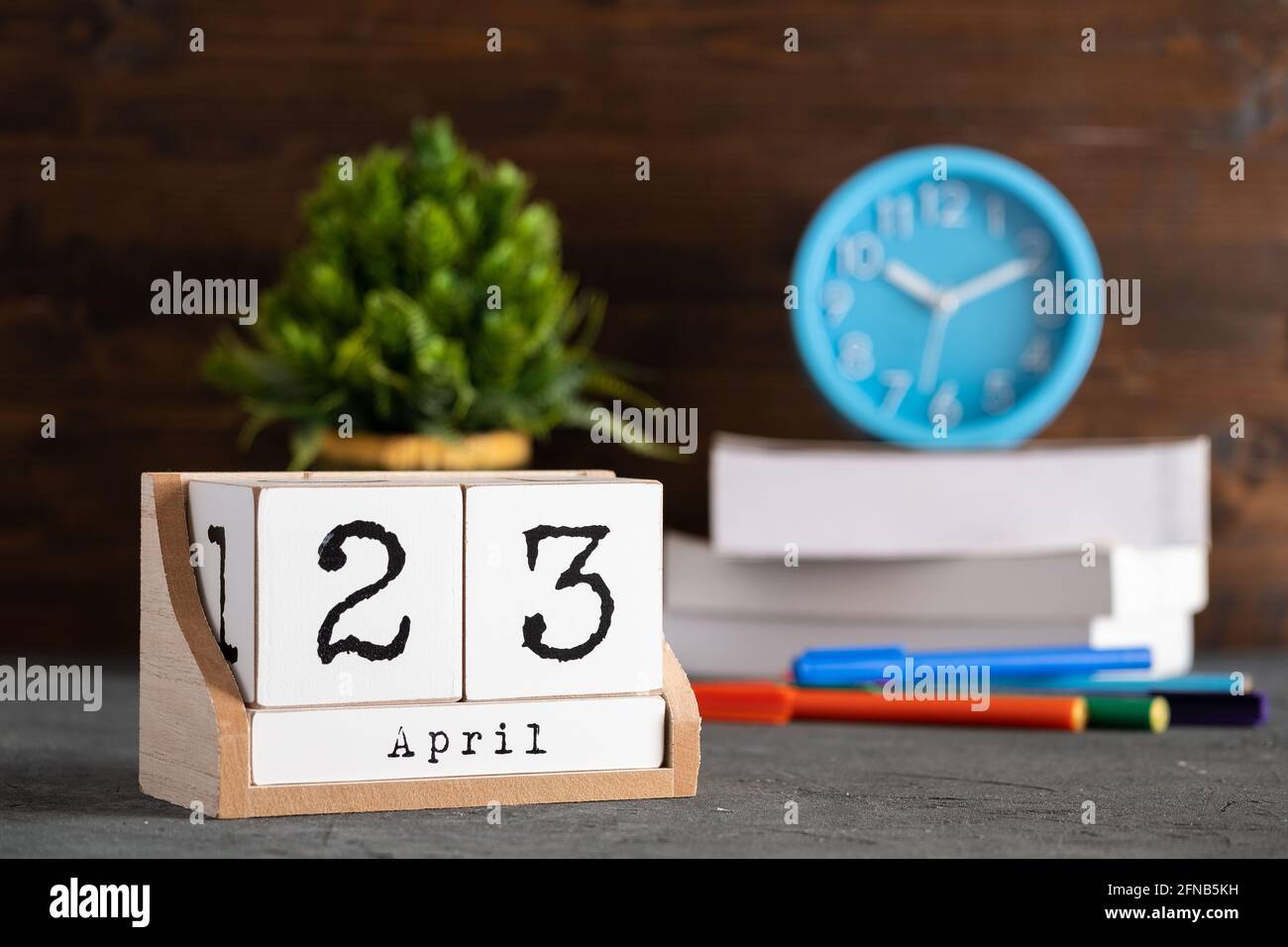 April. April 23 Holzwürfelkalender mit unscharfen Objekten auf dem Hintergrund. Stockfoto