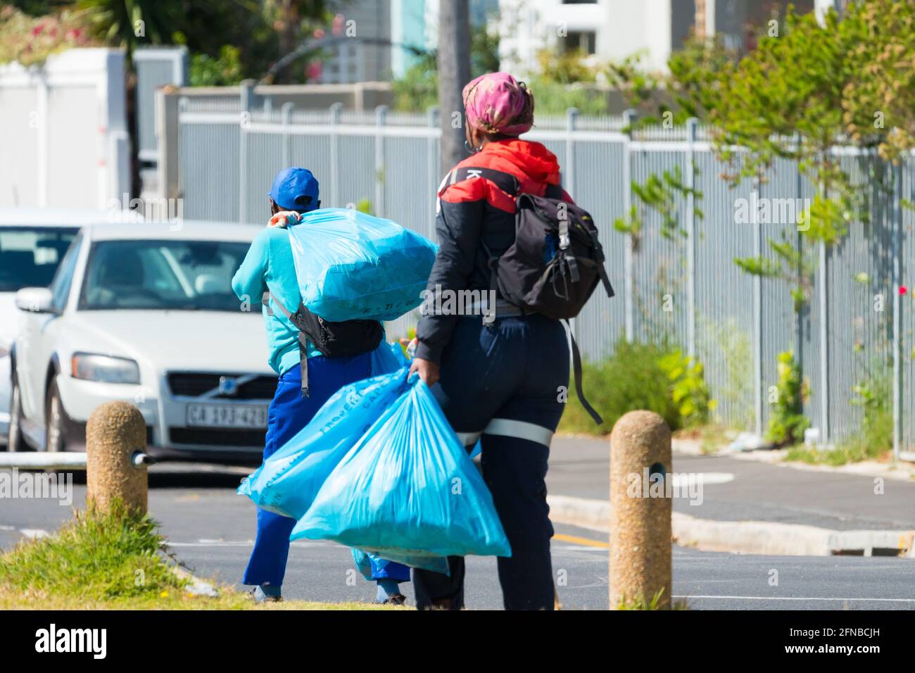 Müllsammler, die während eines Aufreinigungsdienstes in Kapstadt, Südafrika, Abfall oder Müllsäcke auf der Straße transportieren Stockfoto