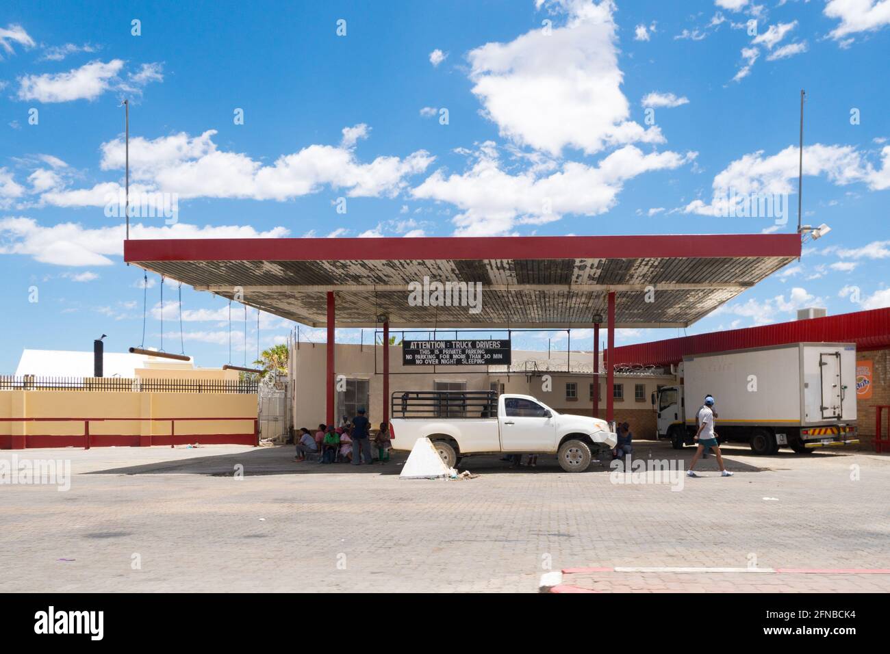 Parkplatz für Fahrzeuge mit afrikanischen Menschen im Schatten sitzen Konzept Alltag in Afrika, Laingsburg, Western Cape, Südafrika Stockfoto