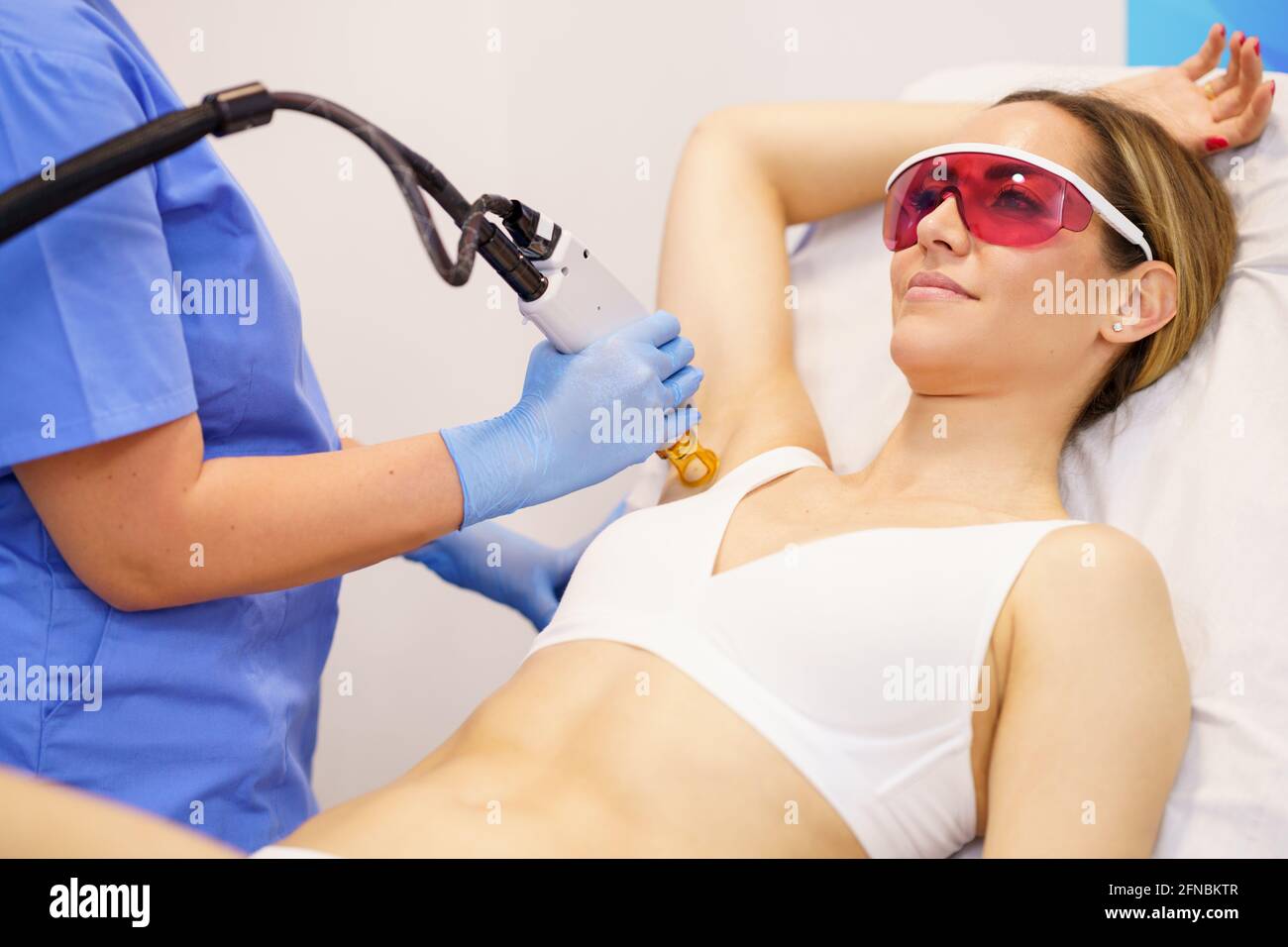 Frau, die in einem Schönheitszentrum Laserhaarentfernung im Achselbereich erhält. Stockfoto