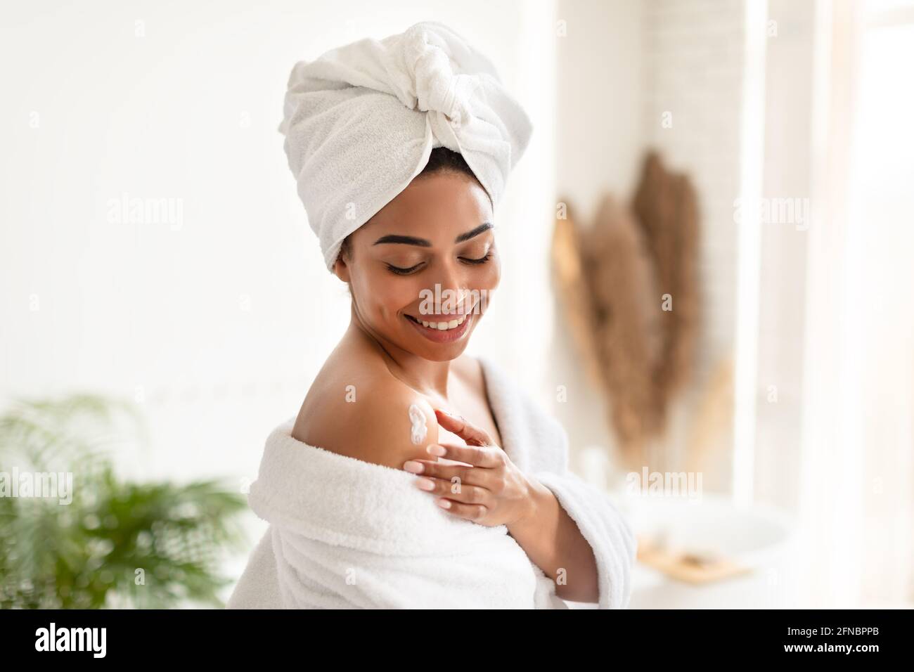 African American Lady Feuchtigkeitsspendende Haut Mit Lotion Im Badezimmer Stockfoto