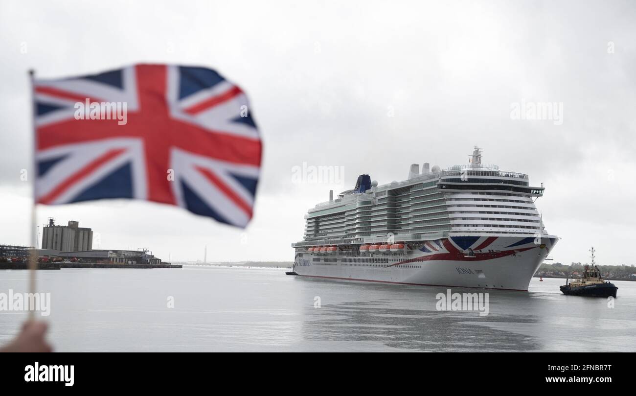 Eine Person schwingt eine Unionsflagge, als das neue P&O-Kreuzschiff Iona vor der Namensgebung zum ersten Mal in Southampton einreist. Iona, das größte für den britischen Markt gebaute Kreuzschiff, ist 345 Meter lang, wiegt 185,000 Tonnen und verfügt über 17 Passagierdecks, was Platz für 5,200 Urlauber schafft. Bilddatum: Sonntag, 16. Mai 2021. Stockfoto