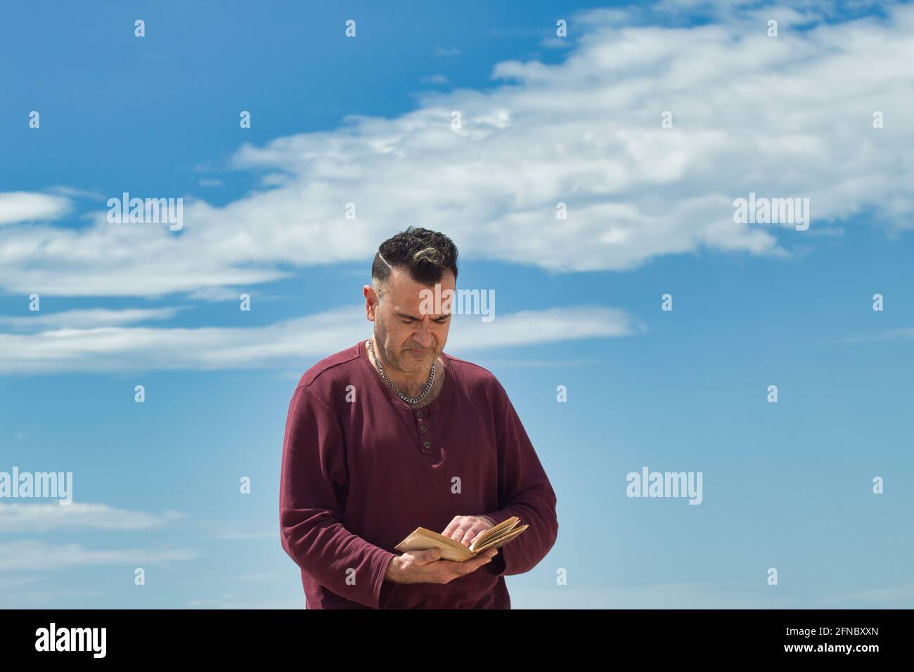 Mann auf dem Sand, der ein Buch über die Küste liest Stockfoto