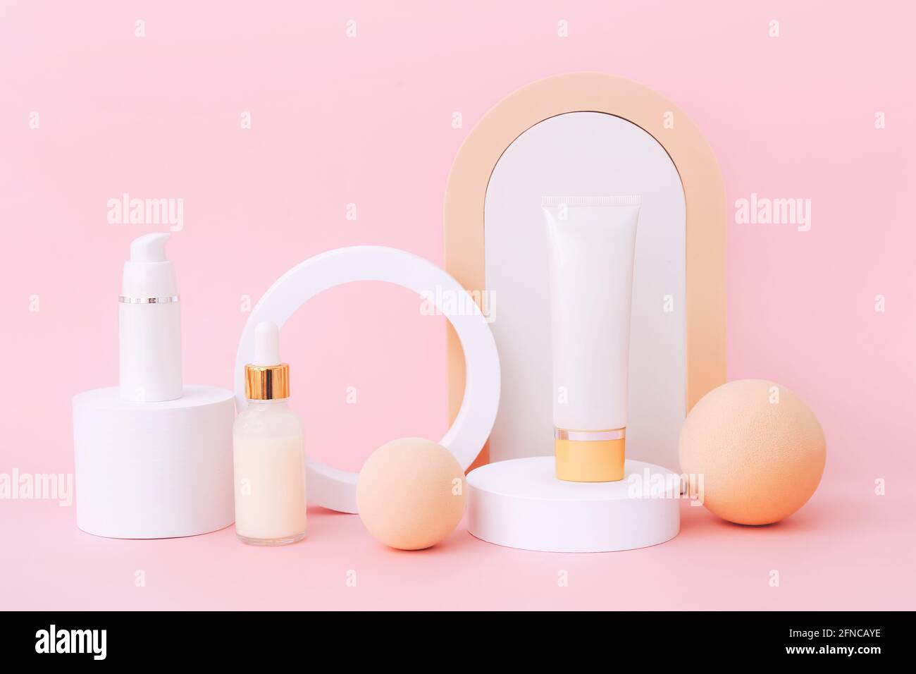 Kosmetische Hautpflegeprodukte bleiben auf den geometrischen Podien. Produktpräsentation auf rosa Hintergrund. Stockfoto