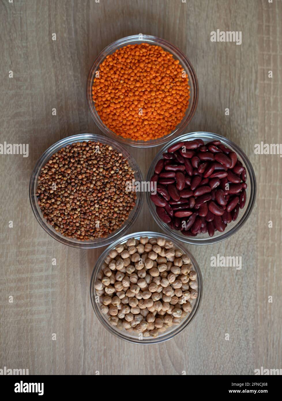 Schalen mit Getreidekörnern: Kichererbsen, rote Linsen, rote Bohnen, Sorghum-Körner Stockfoto