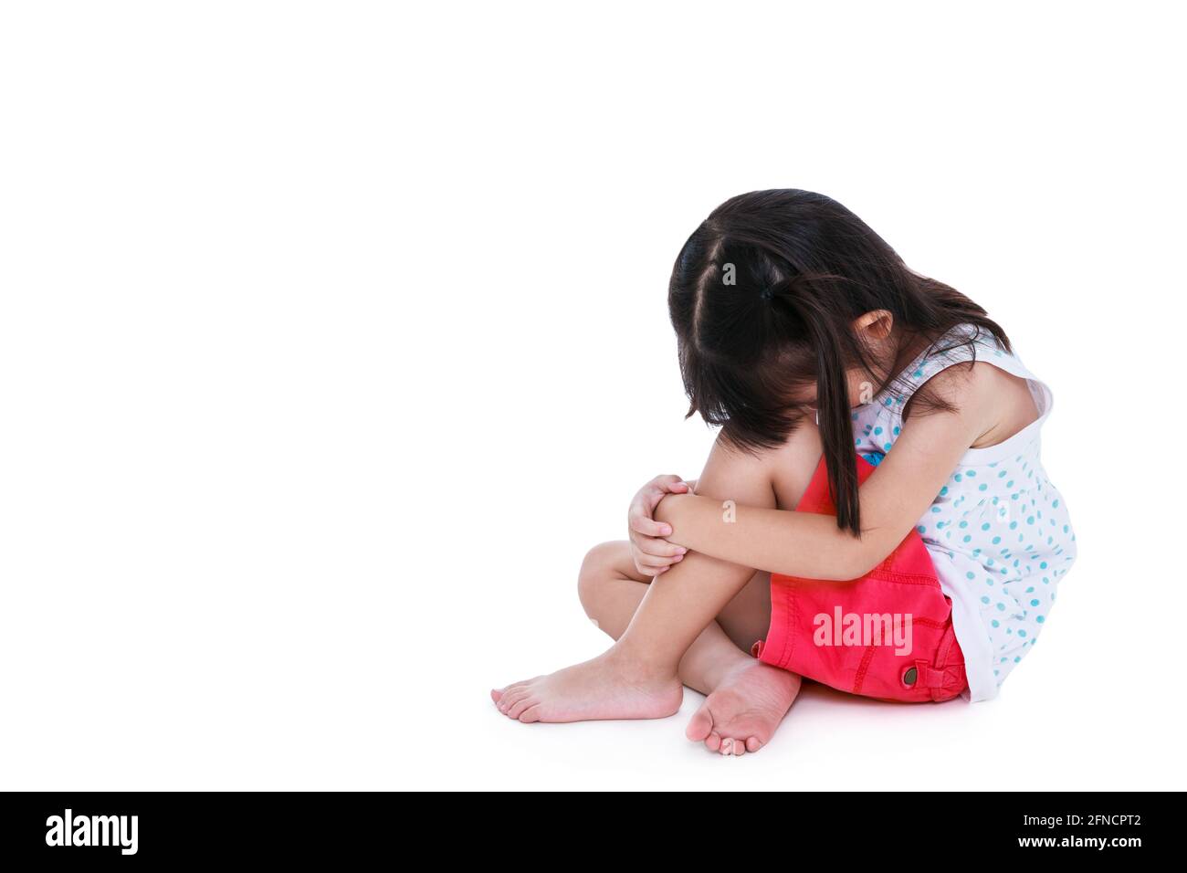 Traurigkeit asiatische Kind barfuß sitzen auf dem Boden mit Kopie Raum. Isoliert auf weißem Hintergrund. Negative menschliche Emotionen. Konzeptionell über Kinder, die la Stockfoto