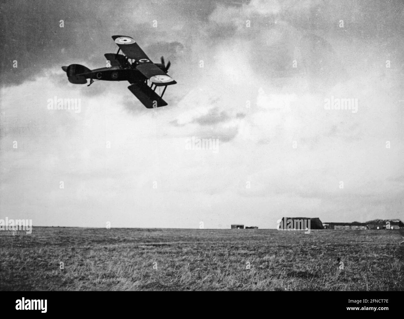 Ein Vintage-Schwarz-Weiß-Foto des Ersten Weltkriegs, das einen britischen Royal Flying Corps Bristol F2B-Kämpfer zeigt, der tief in Richtung eines Flugplatzes fliegt. Stockfoto