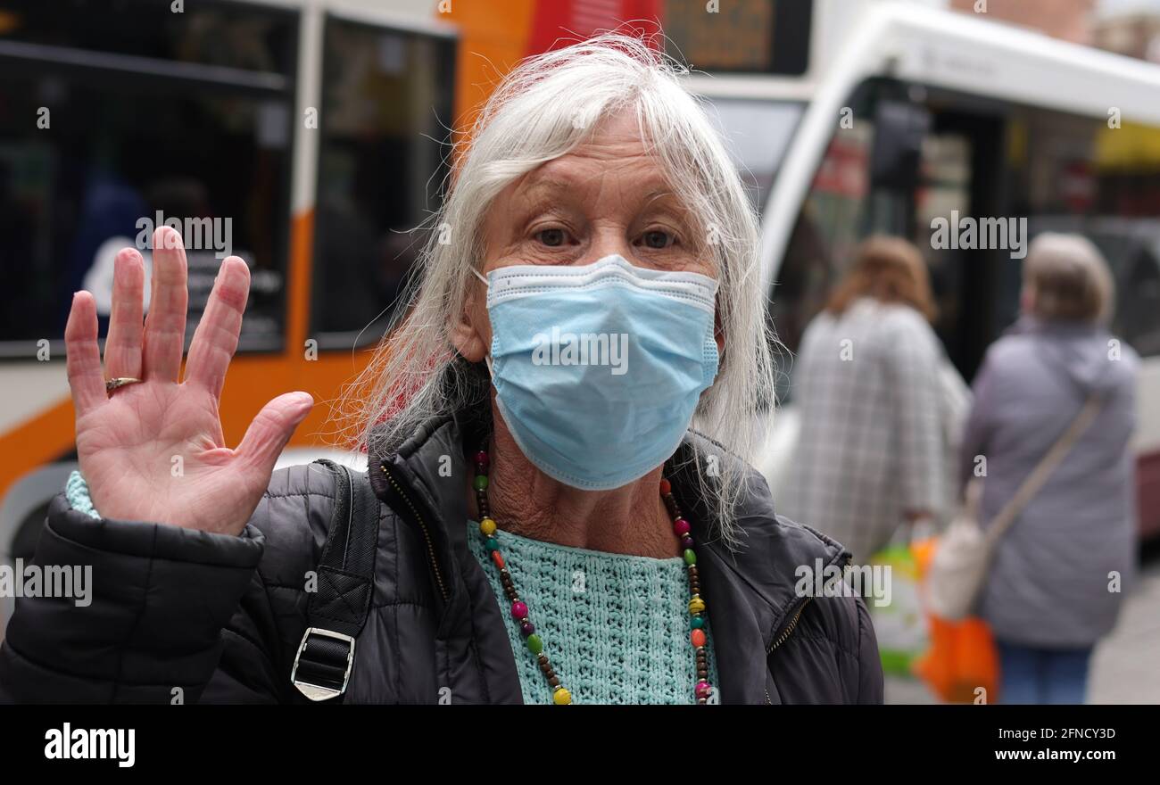 Der Rentner macht eine winkende Geste, bevor er in den Bus fährt. Stockfoto