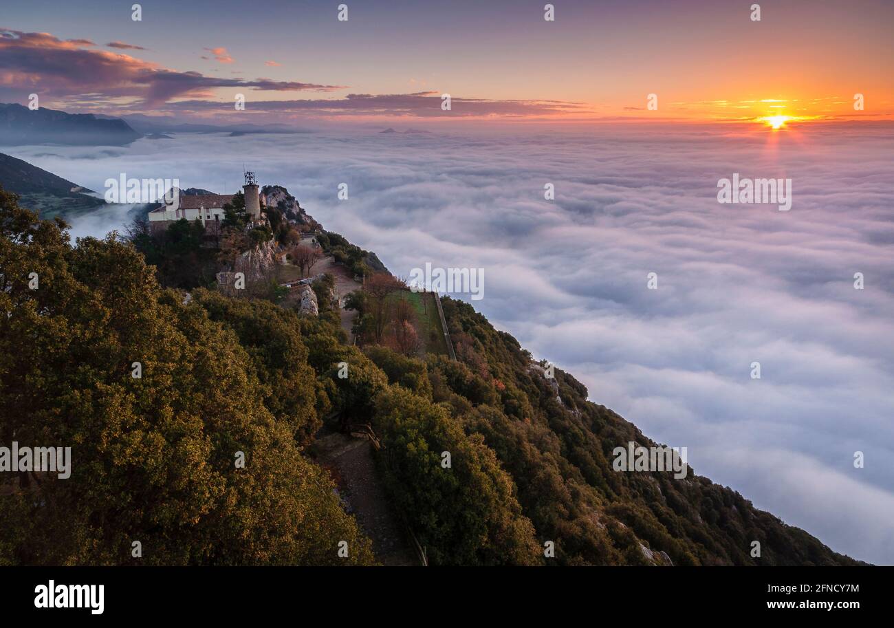 Queralt Sanctuary bei einem Winteraufgang über einem Wolkenmeer betrachtet (Provinz Barcelona, Katalonien, Spanien) ESP: Santuario de Queralt sobre la niebla Stockfoto