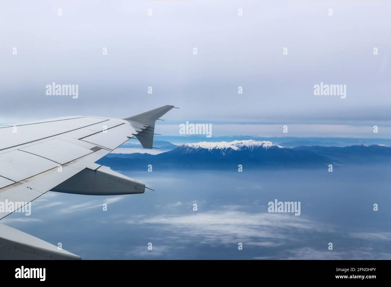 Blick vom Flugzeug mit Flügel über den Berg Olympus Griechenland Mit dem schneebedeckten Gipfel, der durch einen schweren Nebel zeigt Stockfoto