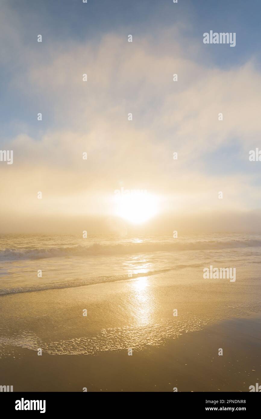 Eine dicke Meeresschicht, die sich während des Sonnenuntergangs zum Ufer bewegt Ein Sandstrand in Kalifornien Stockfoto