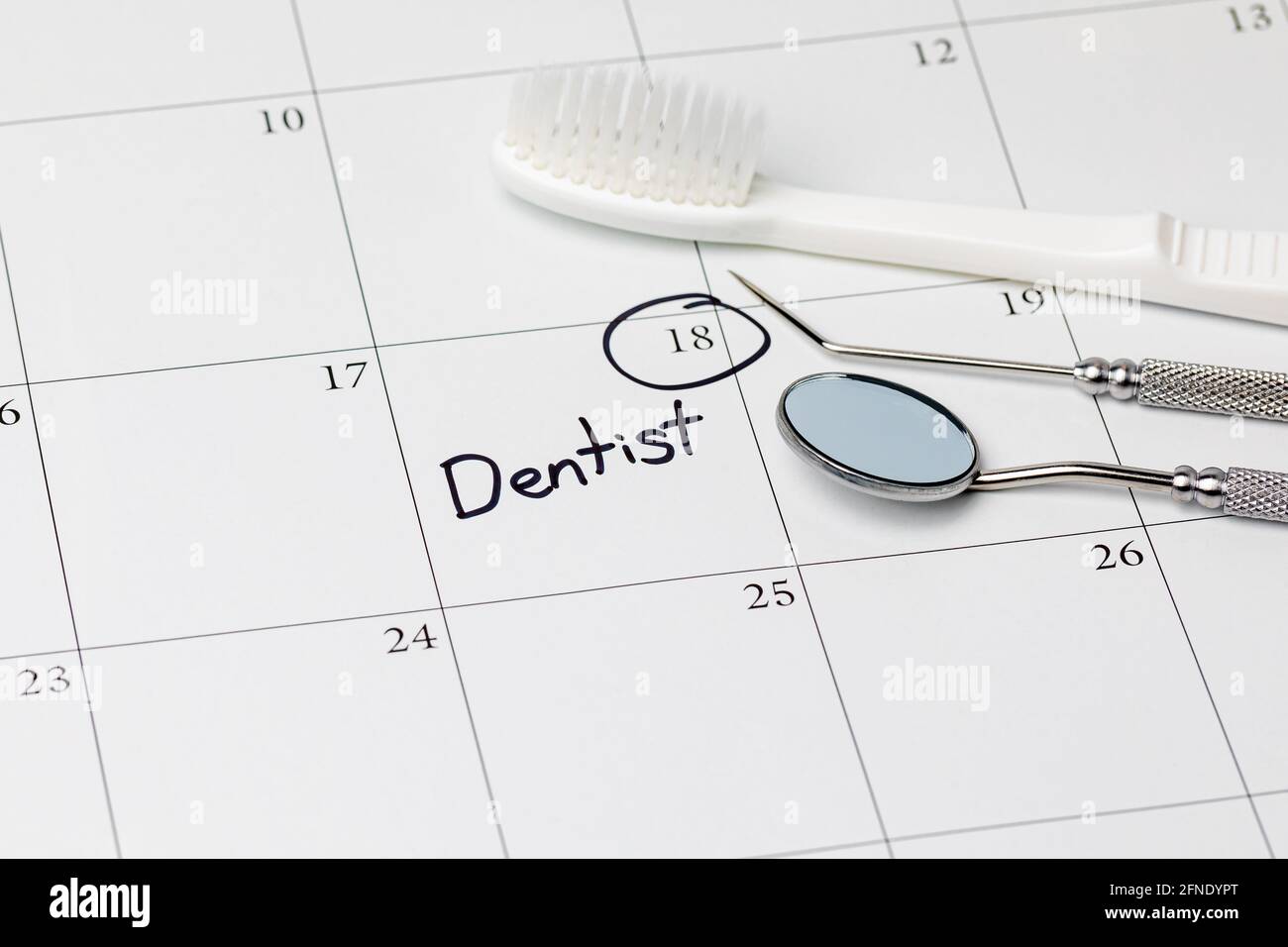 Erinnerung zum Zahnarzttermin auf dem Kalender mit Zahnbürste und Zahnwerkzeugen. Konzept der Mundgesundheit, zahnärztliche Untersuchung und Zahnreinigung Stockfoto