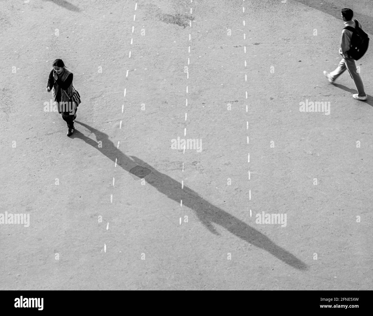 Menschen, die auf der Straße gehen, halten soziale Distanz mit dramatischen Schatten aufrecht. Stockfoto