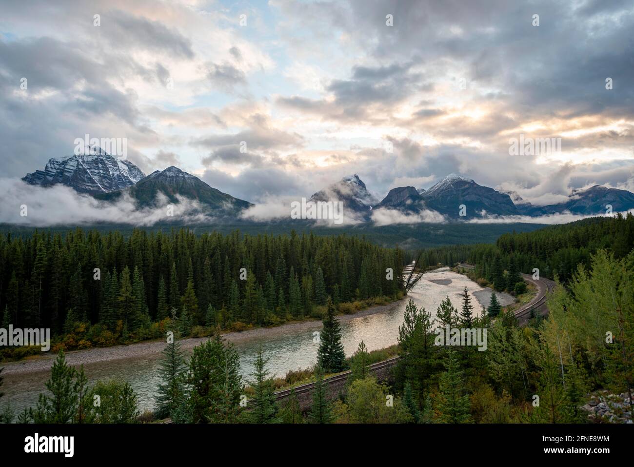 Wolkige Rocky Mountains bei Sonnenuntergang, Morant's Curve, bewaldete Küste am Bow River, Bow Valley, Banff National Park, Alberta, Kanada Stockfoto