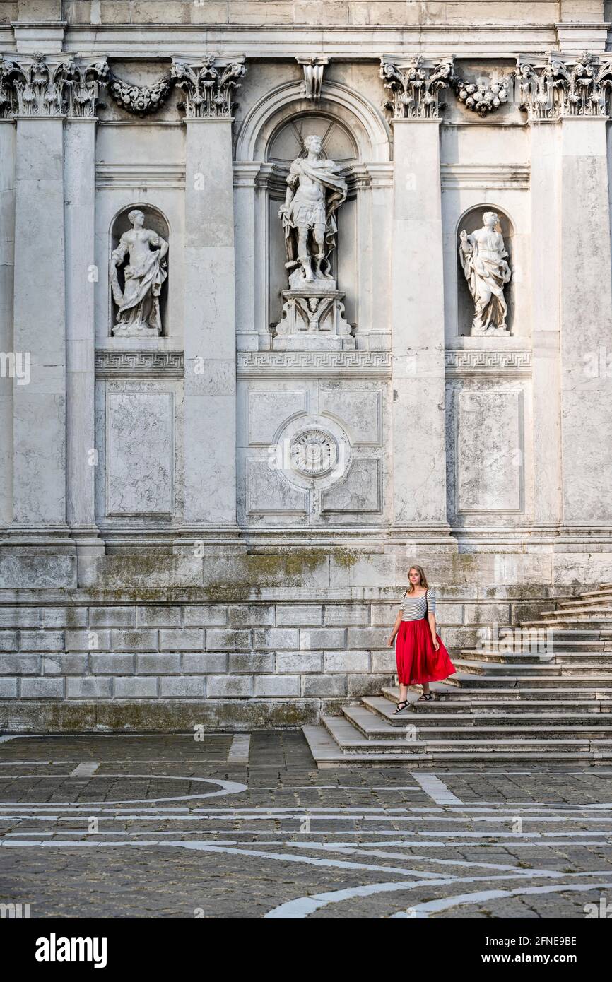 Junge Frau mit rotem Kleid vor der weißen Kirche, Basilica di Santa Maria della Salute, Venedig, Venetien, Italien Stockfoto