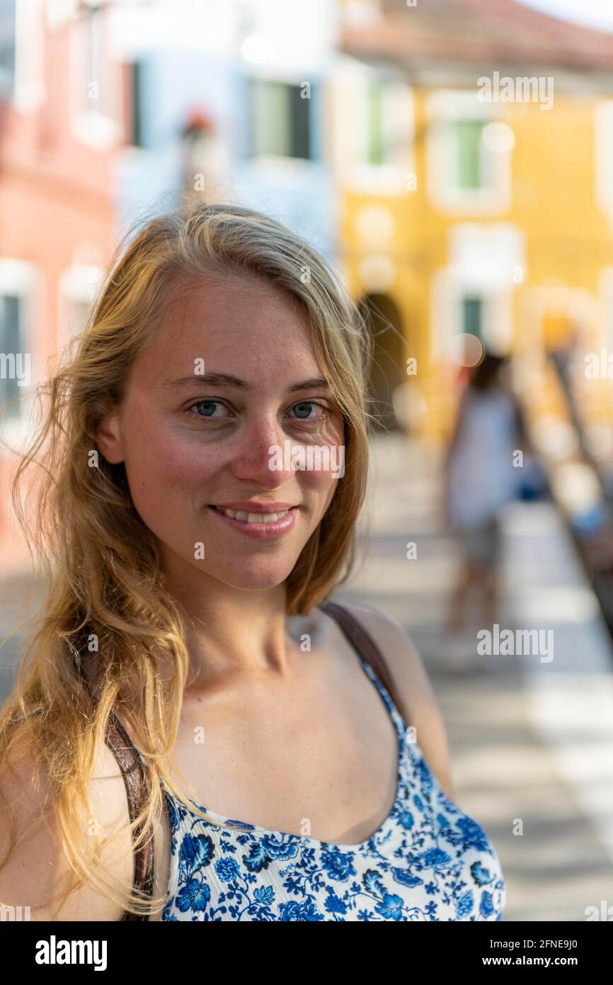 Porträt einer jungen Frau vor einer roten Wand, Blick in die Kamera, Burano Island, Venedig, Venetien, Italien Stockfoto