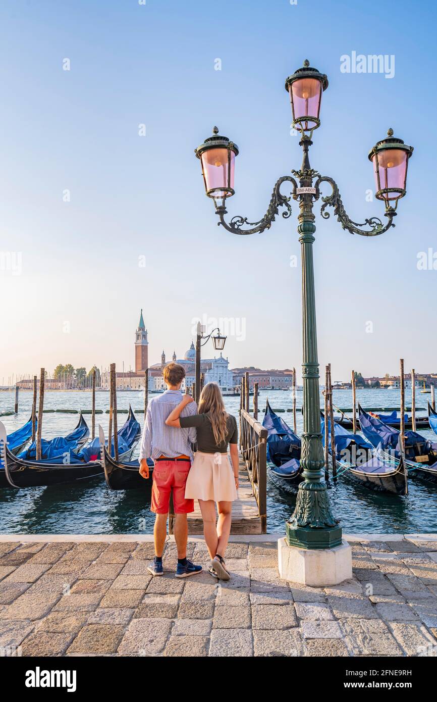 Junges Paar vor einem Steg, venezianische Gondeln, Blick auf die Kirche San Giorgio Maggiore, Venedig, Venetien, Italien Stockfoto