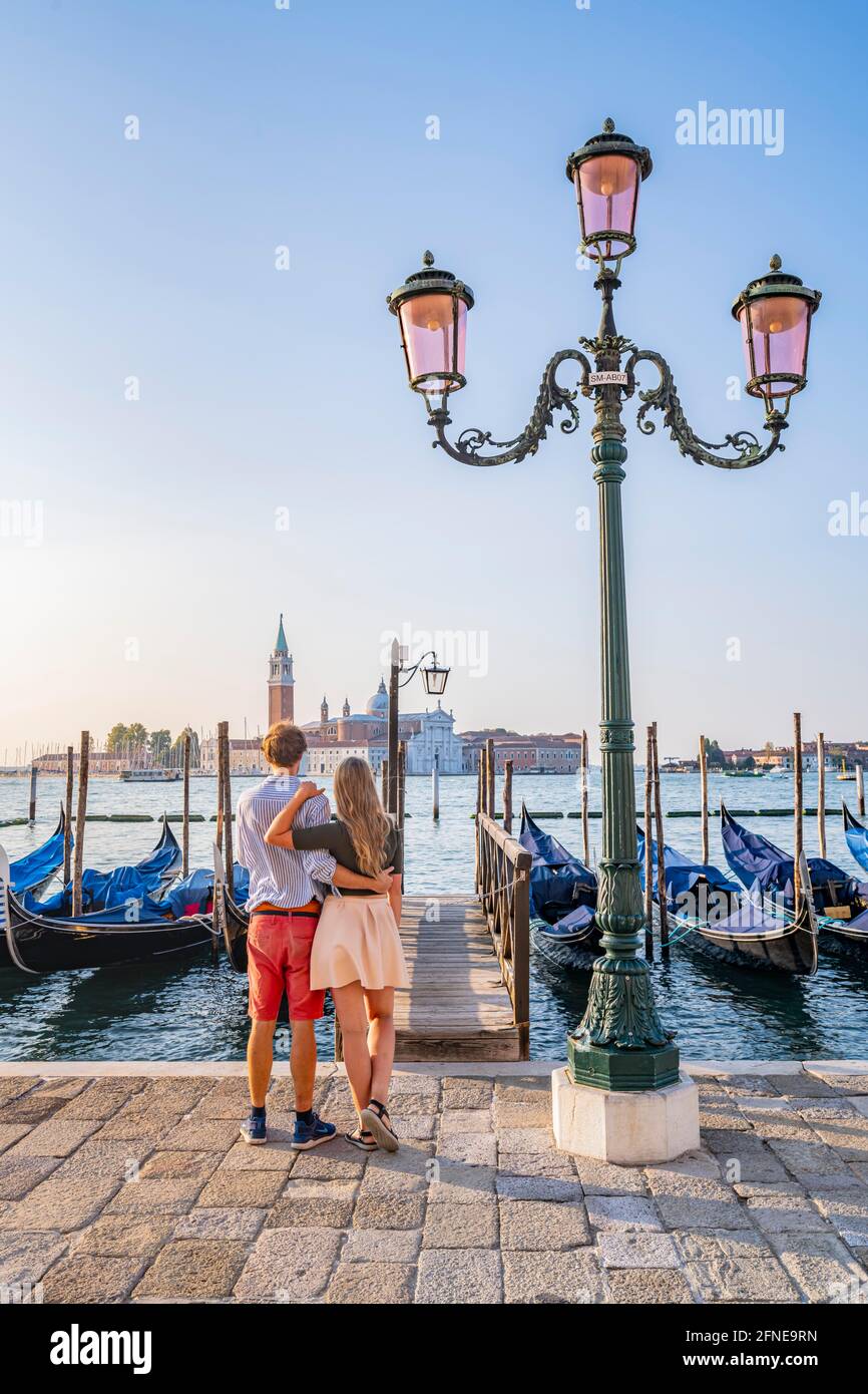 Junges Paar vor einem Steg, venezianische Gondeln, Blick auf die Kirche San Giorgio Maggiore, Venedig, Venetien, Italien Stockfoto