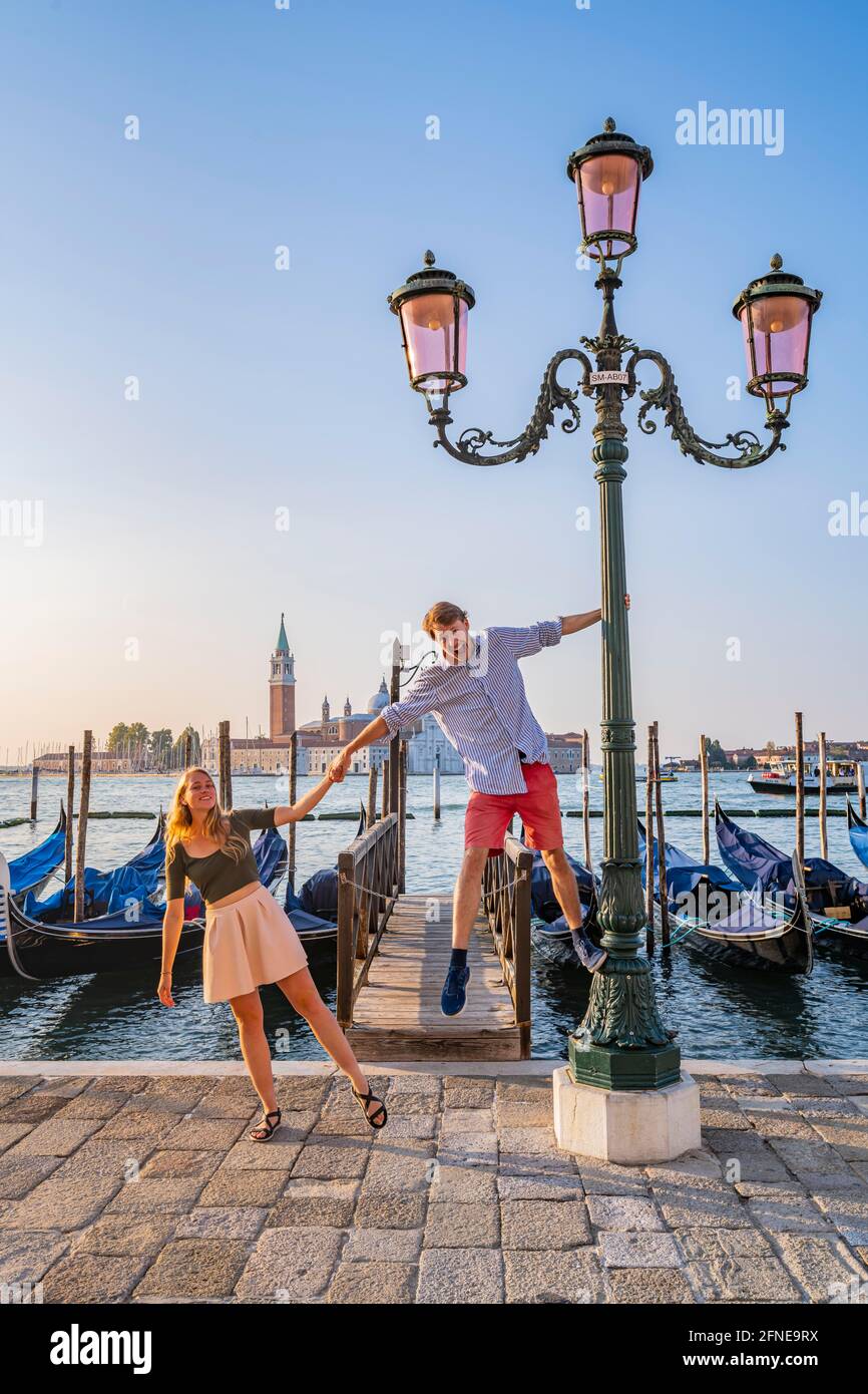 Junges glückliches Paar vor einem Steg, venezianische Gondeln, in der hinteren Kirche San Giorgio Maggiore, Venedig, Venetien, Italien Stockfoto