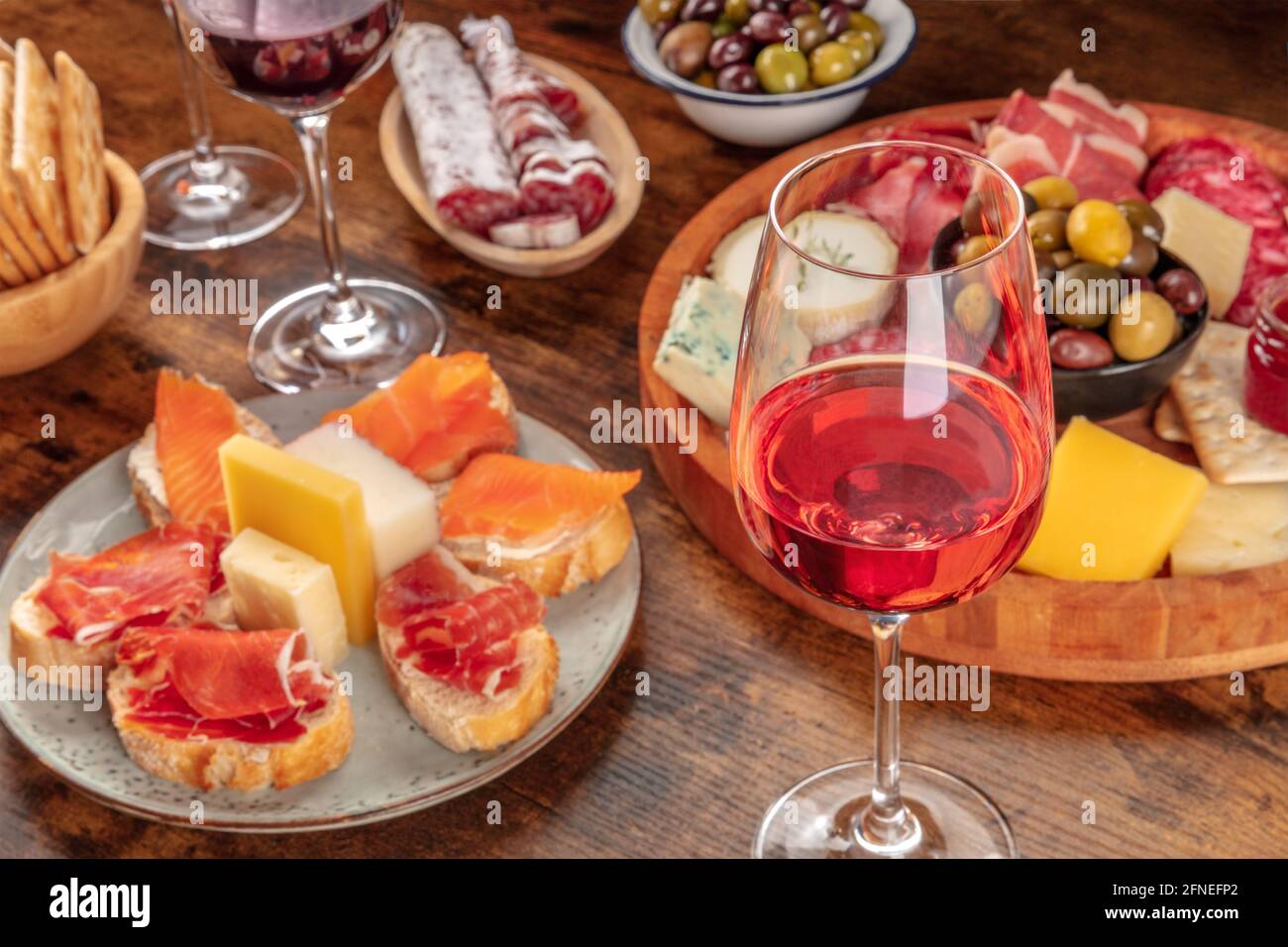 Ein Glas Roséwein mit Sandwiches und einer Käse- und Wurstplatte. Italienische Antipasti oder spanische Tapas. Elegante Gourmet-Vorspeisen Stockfoto