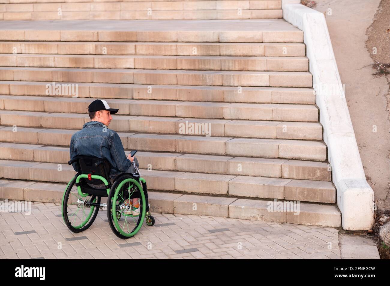 Eine junge behinderte Person im Rollstuhl kann die Treppe nicht betreten. Zugängliche Umgebung für Behinderte Stockfoto