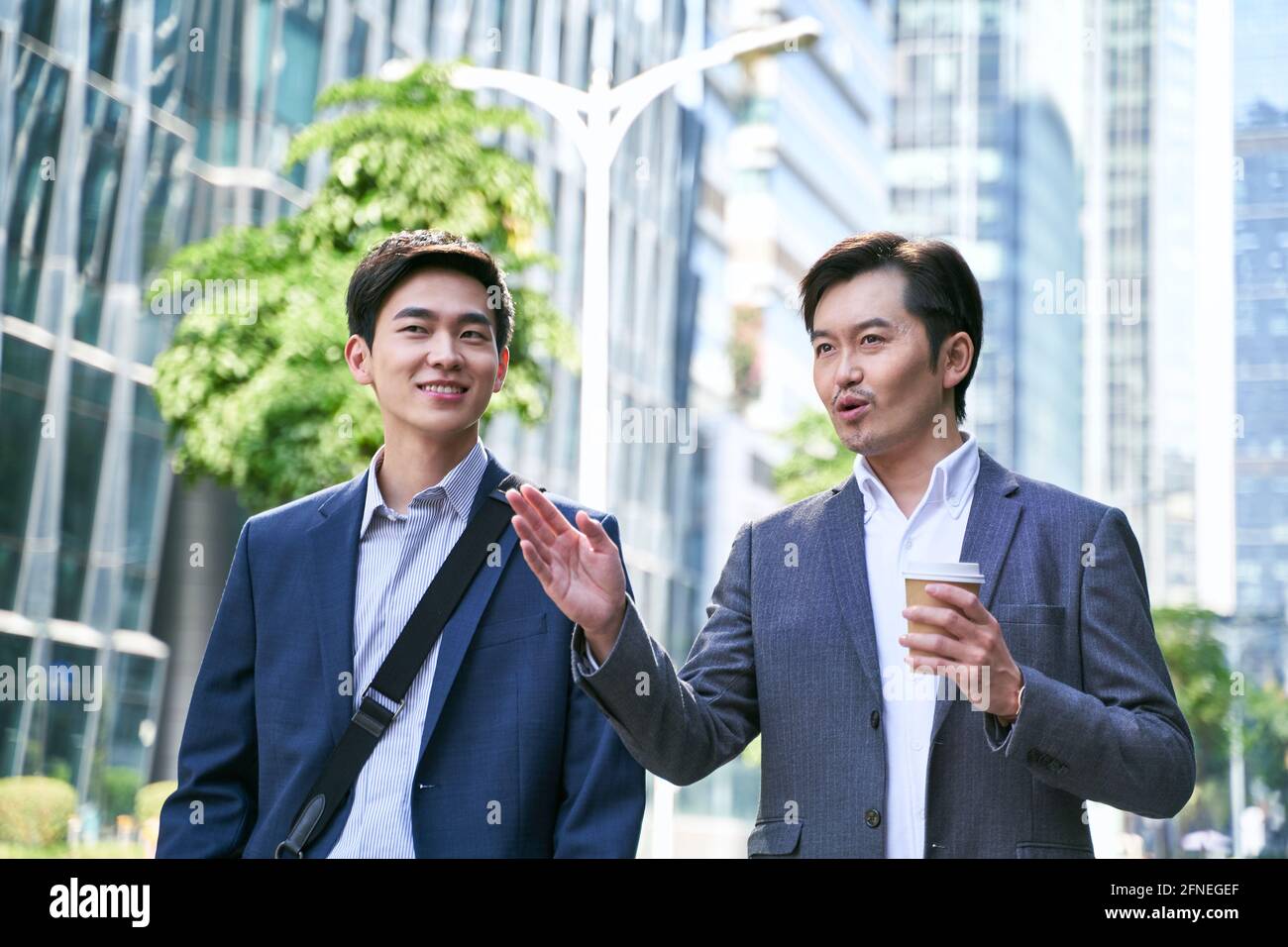 Zwei asiatische Geschäftsleute, die auf der Straße im modernen Stil sprechen Stadt Stockfoto