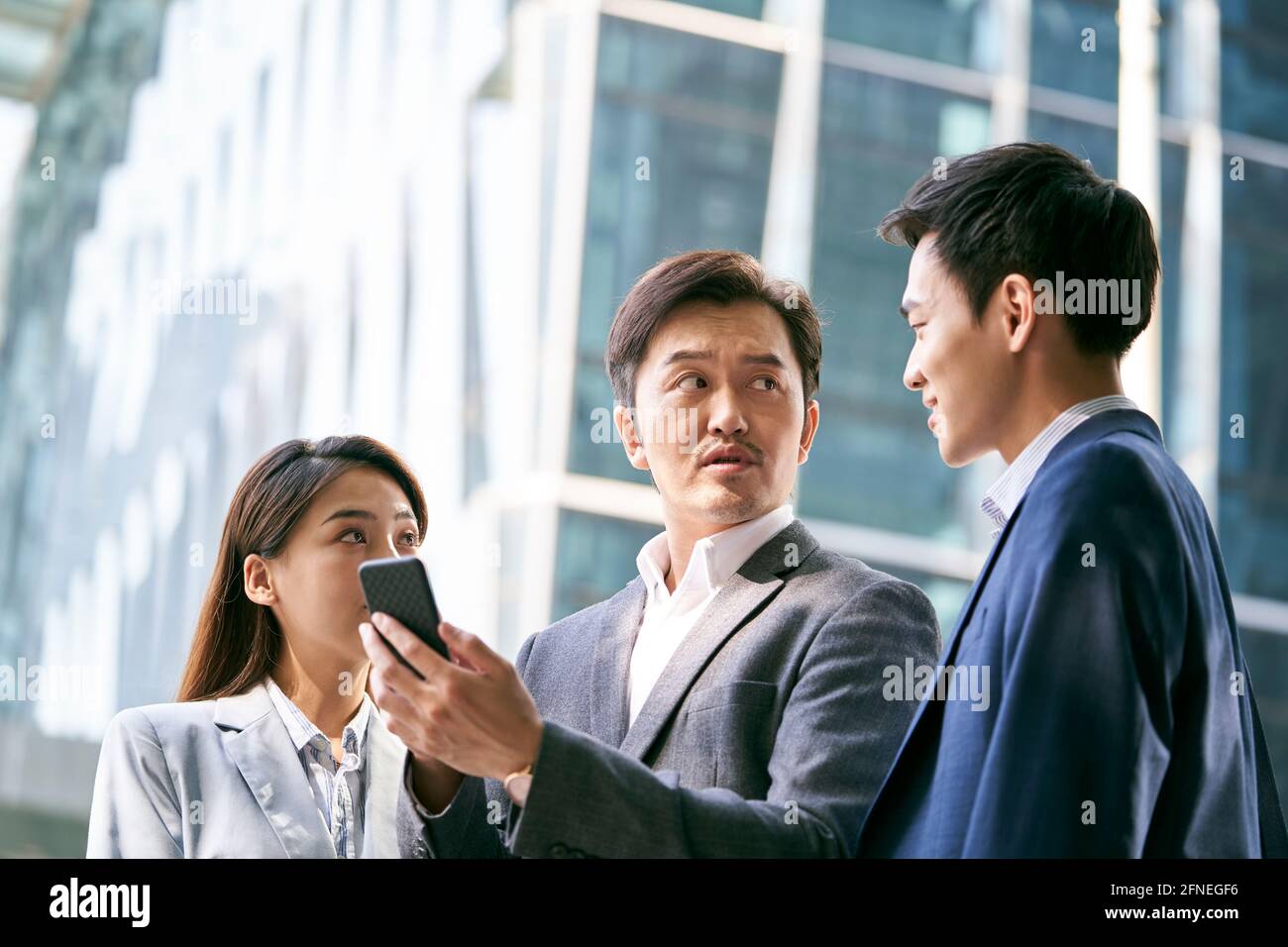 Ein Team asiatischer Geschäftsleute, die auf der Straße stehen Eine Diskussion mit dem Handy in der Innenstadt Stockfoto