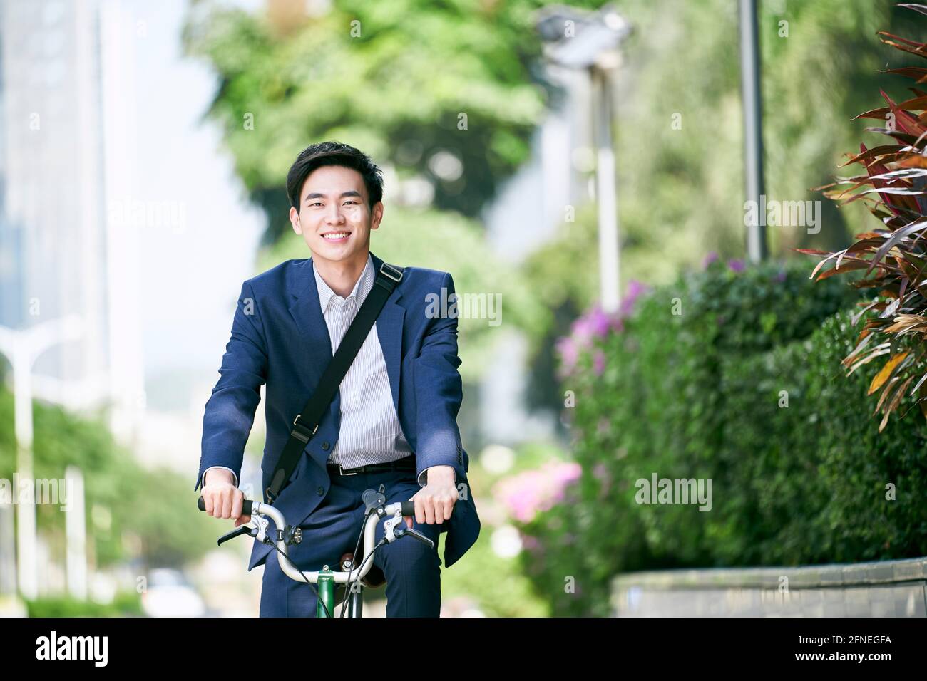 Junge asiatische Geschäftsführerin, die mit dem Fahrrad glücklich und lächelnd pendelt Stockfoto