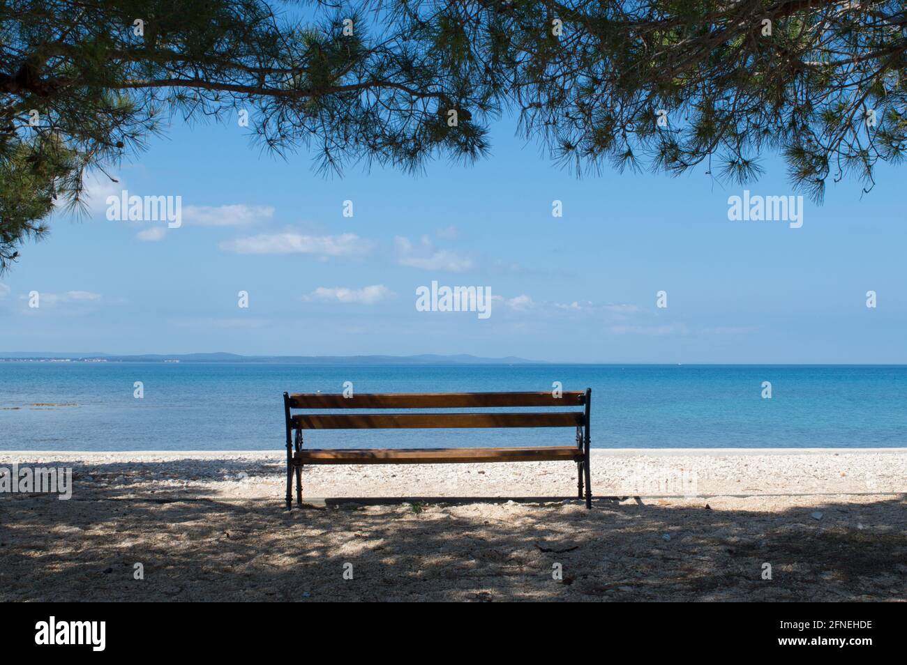 Leere Holzbank mit dem entspannenden Blick auf die blaue Adria, ruhige Szene in Zadar, Kroatien Stockfoto