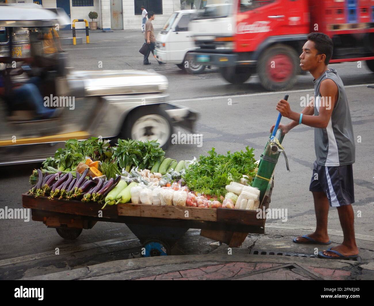 Mann schiebt einen Gemüsewagen auf der Straße von Novaliches, Manila, Philippinen Stockfoto