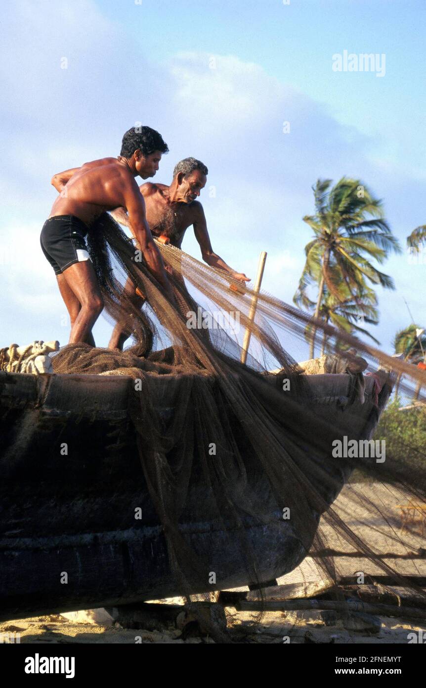 Vater und Sohn sortieren die Netze für den nächsten Fang. Neben dem Tourismus sind Fischerei, Landwirtschaft und Viehzucht die wichtigsten Einkommensquellen für die Menschen im indischen Bundesstaat Goa.n [automatisierte Übersetzung] Stockfoto