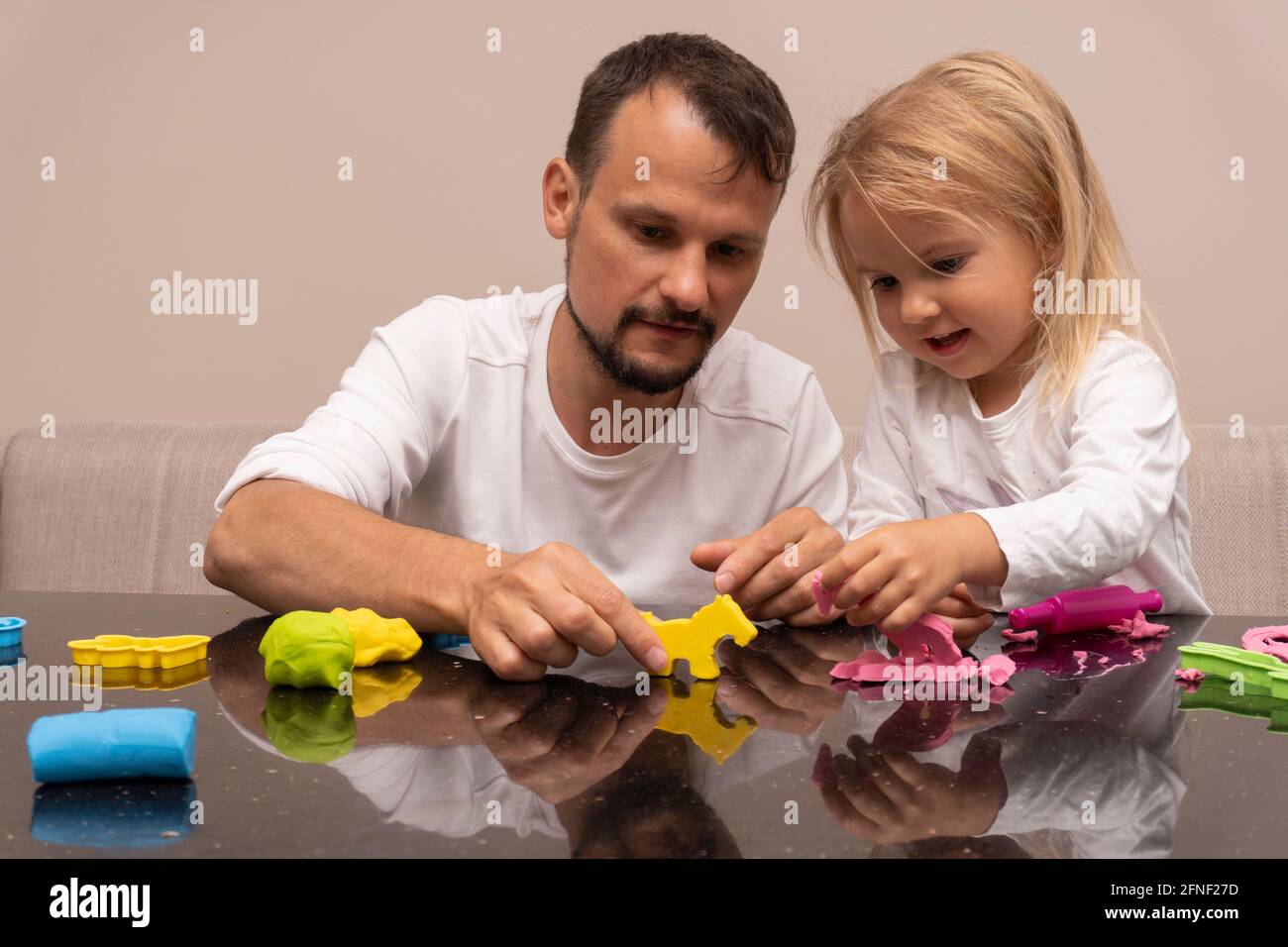 Vater spielt mit Kind mit bunten Tieren aus Spielteig Stockfoto
