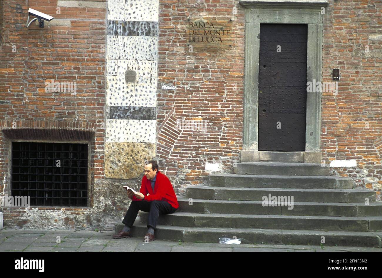 Ein Mann, der auf einer Treppe in Lucca liest. [Automatisierte Übersetzung] Stockfoto