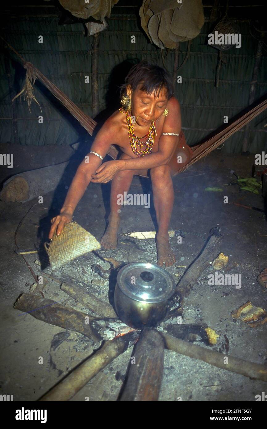 Eine Frau des Yanomami-Stammes lüftelt im Küchenzelt des Kamins, auf dem ein Kochtopf steht. [Automatisierte Übersetzung] Stockfoto