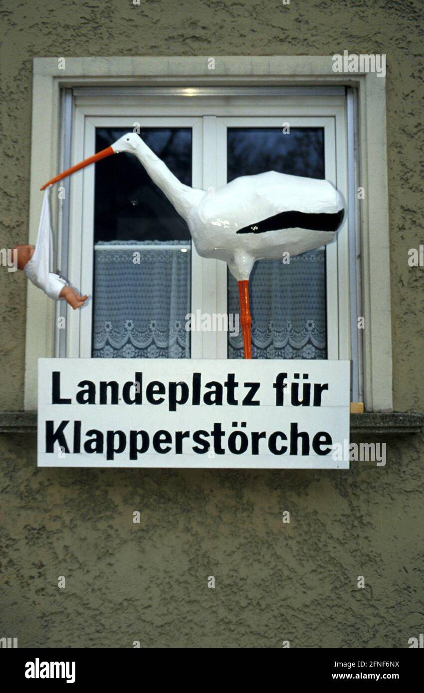 Figur eines klappernden Storches mit Baby in einem Fensterrahmen am Kölner Platz. [Automatisierte Übersetzung] Stockfoto