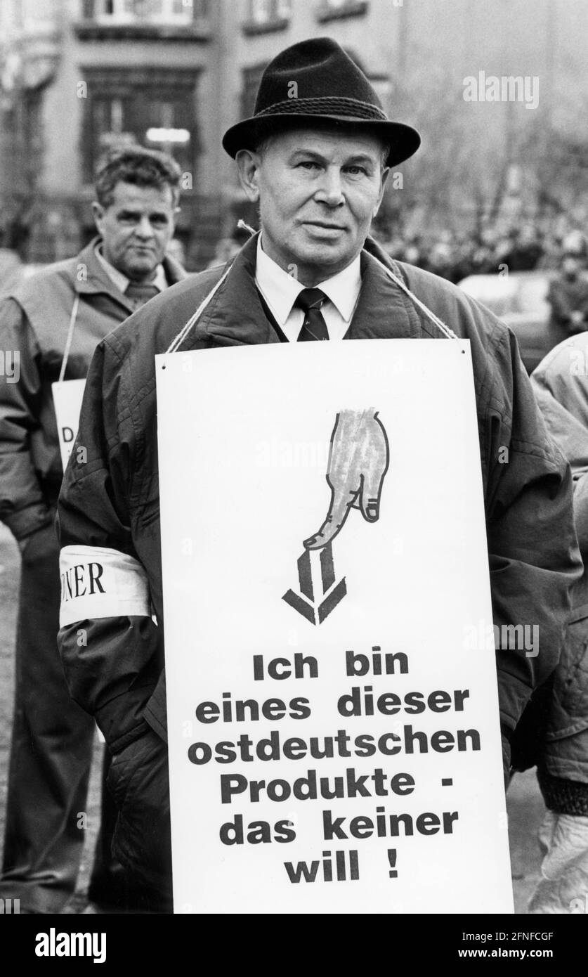 „bei einer Protestkundgebung der IG-Metall versammeln sich Arbeiter vor dem Messegelände zur Eröffnung einer Messe der Treuhand-Unternehmen und eines Geschäftskongresses der Treuhandanstalt. Ein Mann trägt ein Transparent mit der Aufschrift: 'Ich bin eines dieser ostdeutschen Produkte - das niemand will!' Und ein Armband. [Automatisierte Übersetzung]' Stockfoto