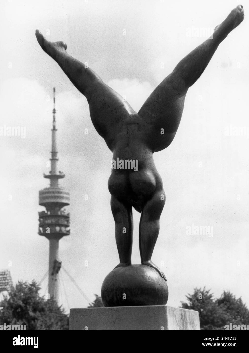 'Illustration der Bronzeskulptur ''Olympia Triumphans'' von Martin Meyer, die 1972 im Münchner Olympiapark errichtet wurde. Eine Sportlerin balanciert mit ihren Händen auf einem Ball. Im Hintergrund der Münchner Olympiaturm. [Automatisierte Übersetzung]' Stockfoto
