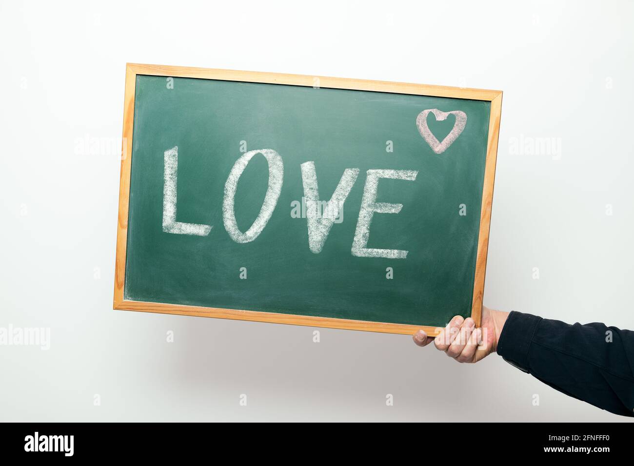 Hand hält eine Tafel mit dem Wort LIEBE handgeschrieben Kreide Stockfoto