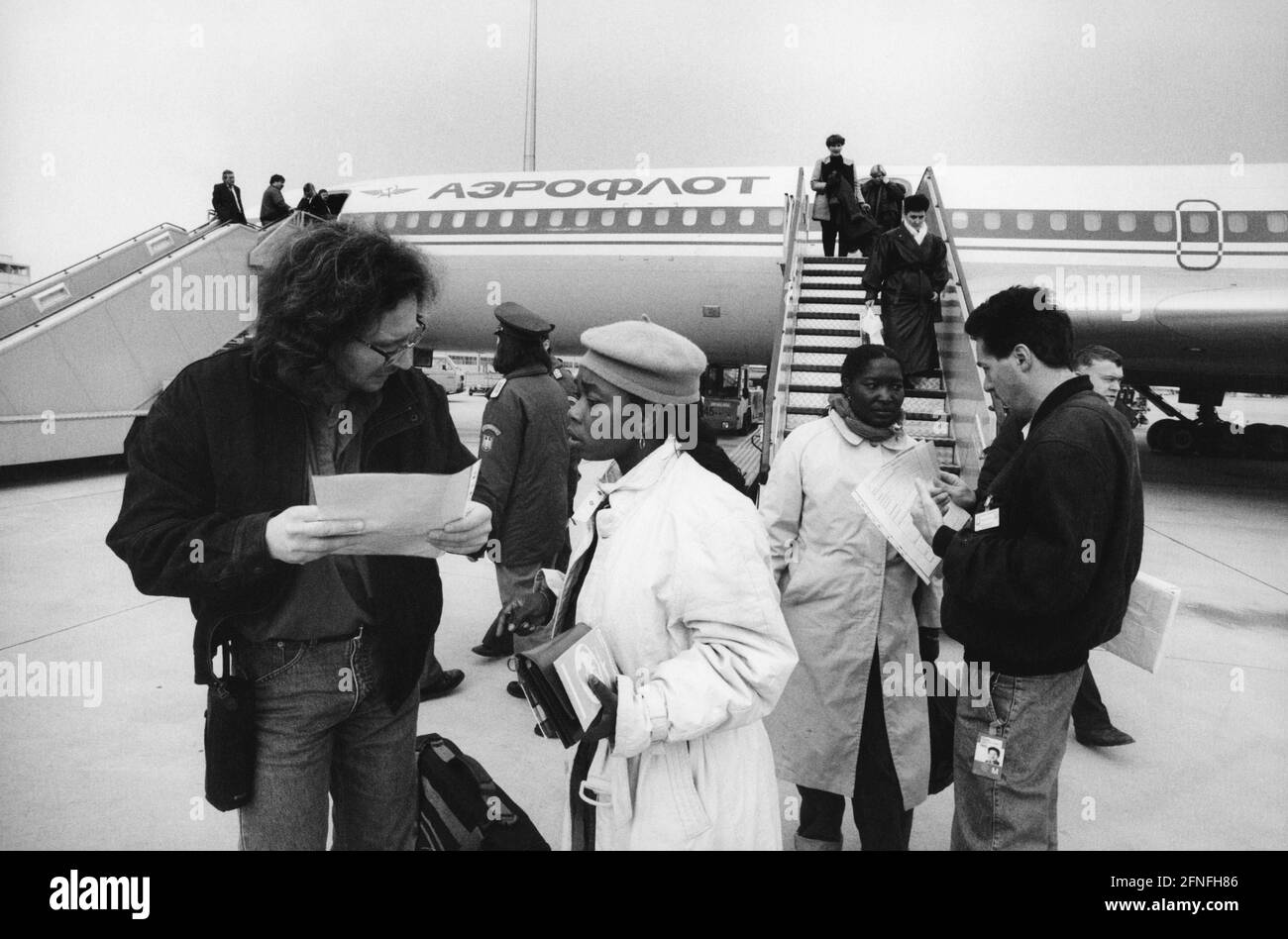 Mitglieder der Sozialdienste empfangen Flüchtlinge aus Togo am Franz-Josef-Strauß-Flughafen München, die mit einem Aeroflot-Flugzeug aus Moskau angekommen waren. [Automatisierte Übersetzung] Stockfoto