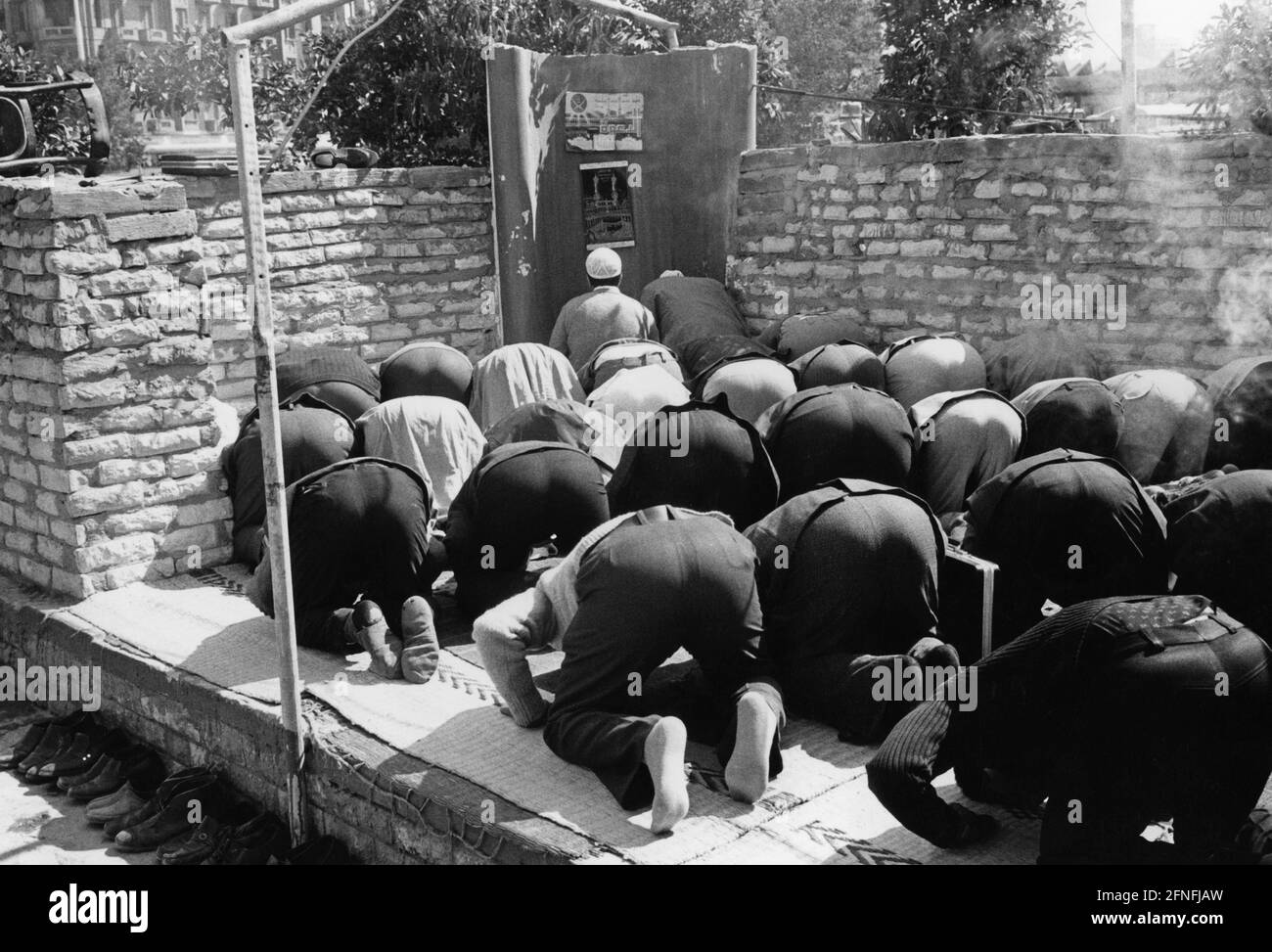 In einer Nische in der Mauer im Zentrum von Kairo knien Männer vor einem provisorischen Mirabben nach Mekka. In der Nische hängt ein Bild der Moschee in Mekka. [Automatisierte Übersetzung] Stockfoto