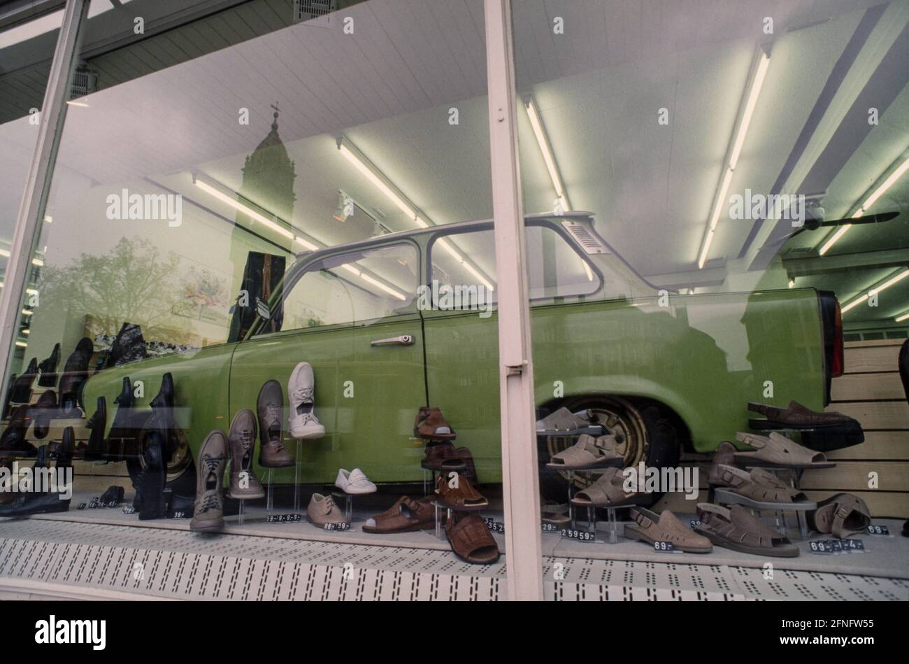 Schaufenster in einem Neuköllner Schuhgeschäft mit Trabant Karosserie zur Dekoration. Das Rathaus Neukölln in der Neonreflexion. Fotografie um 1991 [automatisierte Übersetzung] Stockfoto