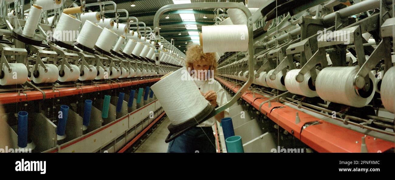 Sachsen-Anhalt / Industrie / DDR / Leuna 1995. Die DOMO Group (Carpets) hat ein neues Werk zur Herstellung von Teppichfasern errichtet. Das Foto zeigt die Spinnerei. Die Garne werden auf den Garnrollen aufgewickelt. Die Frauen müssen neue Rollen einlegen, das Garn fädeln und es greifen, wenn es zusammenbricht. Typische Frauenarbeit. Die Fabrik wurde auf dem alten VEB-Gelände gebaut, auf dem heute viele Unternehmen leben. Erfolgreich privatisiert von der Treuhand // Sachsen-Anhalt / Wirtschaft / Frauen / Textil / 1916 baut BASF aus Ludwigshafen eine Ammoniakfabrik in der Nähe des Dorfes Leuna. 1924 wird eine Methanolanlage zugesetzt und Stockfoto