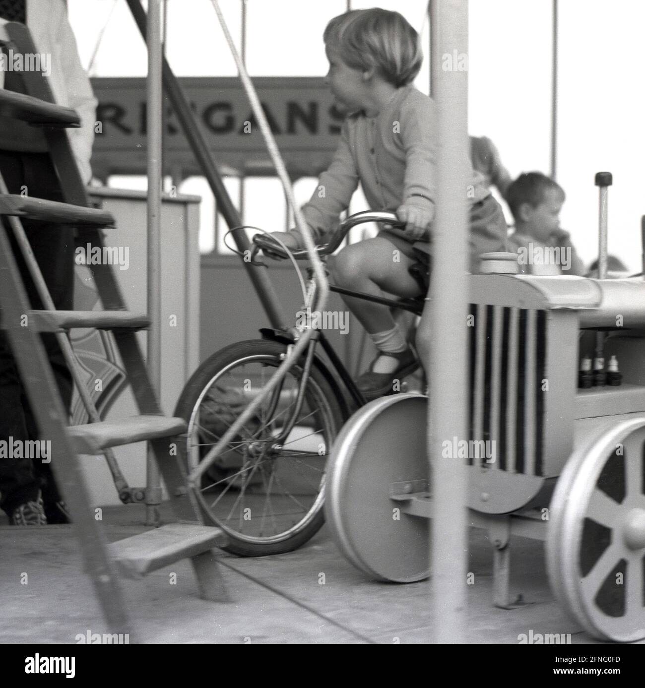 In den 1950er Jahren, historisch, ein Kind, das auf einem festen Fahrrad auf einer Kirmes-Fahrt sitzt, England, Großbritannien. Stockfoto