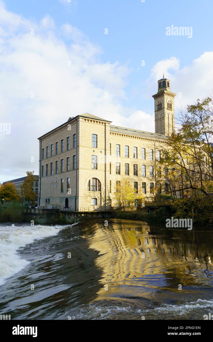 Blick auf die Salz Mill (ehemals Textilfabrik), die 1853 gebaut wurde, mit dem Aire River Weir im Vordergrund, Shipley, West Yorkshire, Großbritannien. Stockfoto