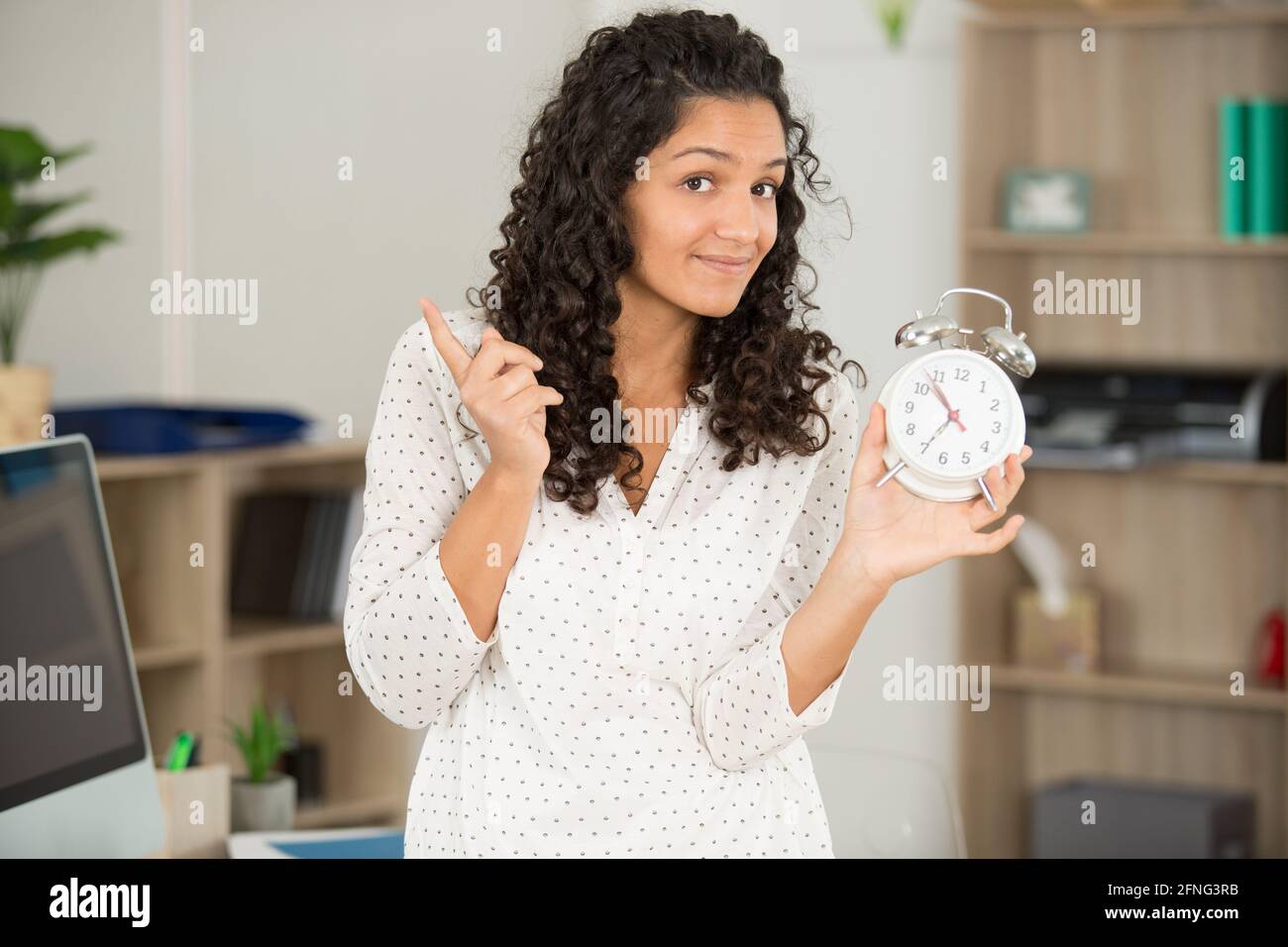 Frau mit Wecker im Bürozeitmanagement-Konzept Stockfoto