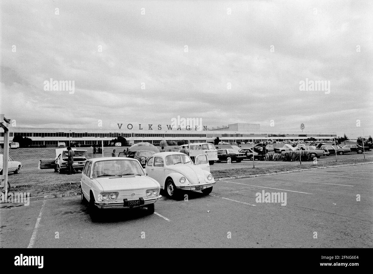 Parkplatz vor dem VW-Werk in Puebla. Das Wort 'Volkswagen' ist in Großbuchstaben auf dem Gebäude angebracht. [Automatisierte Übersetzung]' Stockfoto